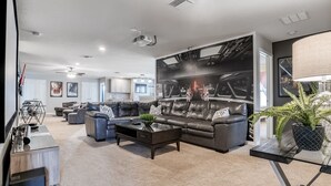 A modern living room with a large sectional sofa, a coffee table, and a flat-screen TV. - Fun, dog-friendly home with private pool, high-speed WiFi, W/D, & game rooms (Kissimmee)