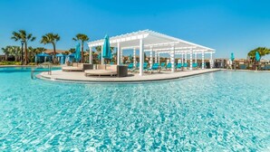 A clear blue pool with a white pergola and lounge chairs, surrounded by palm trees and umbrellas. - Fun, dog-friendly home with private pool, high-speed WiFi, W/D, & game rooms (Kissimmee)