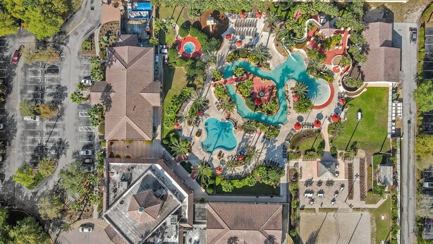 Vista aérea de un resort con una gran piscina, varias toboganes acuáticos y un estacionamiento.