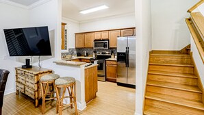 Una cocina moderna con armarios de madera, electrodomésticos de acero inoxidable y una isla integrada con taburetes.