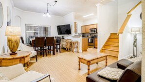 Amplia sala de estar con comedor, cocina y escalera.