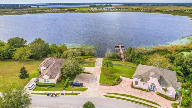 A large body of water with a residential area in the foreground, including houses and a driveway. - Vibrant modern home with private pool, spa, lanai & expansive game room (Haines City)