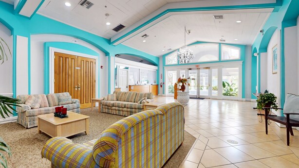 A spacious lobby with a high ceiling, a reception desk, and multiple seating areas. - Comfortable townhome near Disney with athletic courts & pool access, patio, & AC (Davenport)