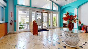 A hotel lobby with a reception desk, a glass-top table with a decorative vase, and a large window with a view of the outdoors. - Comfortable townhome near Disney with athletic courts & pool access, patio, & AC (Davenport)