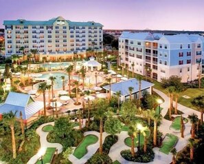 A hotel with multiple buildings, a swimming pool, and landscaped gardens. - Spacious condo with themed rooms, foosball table and shared pool (Kissimmee)