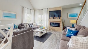 Un salon moderne avec un ensemble de canapés, une table basse et un téléviseur fixé au mur.