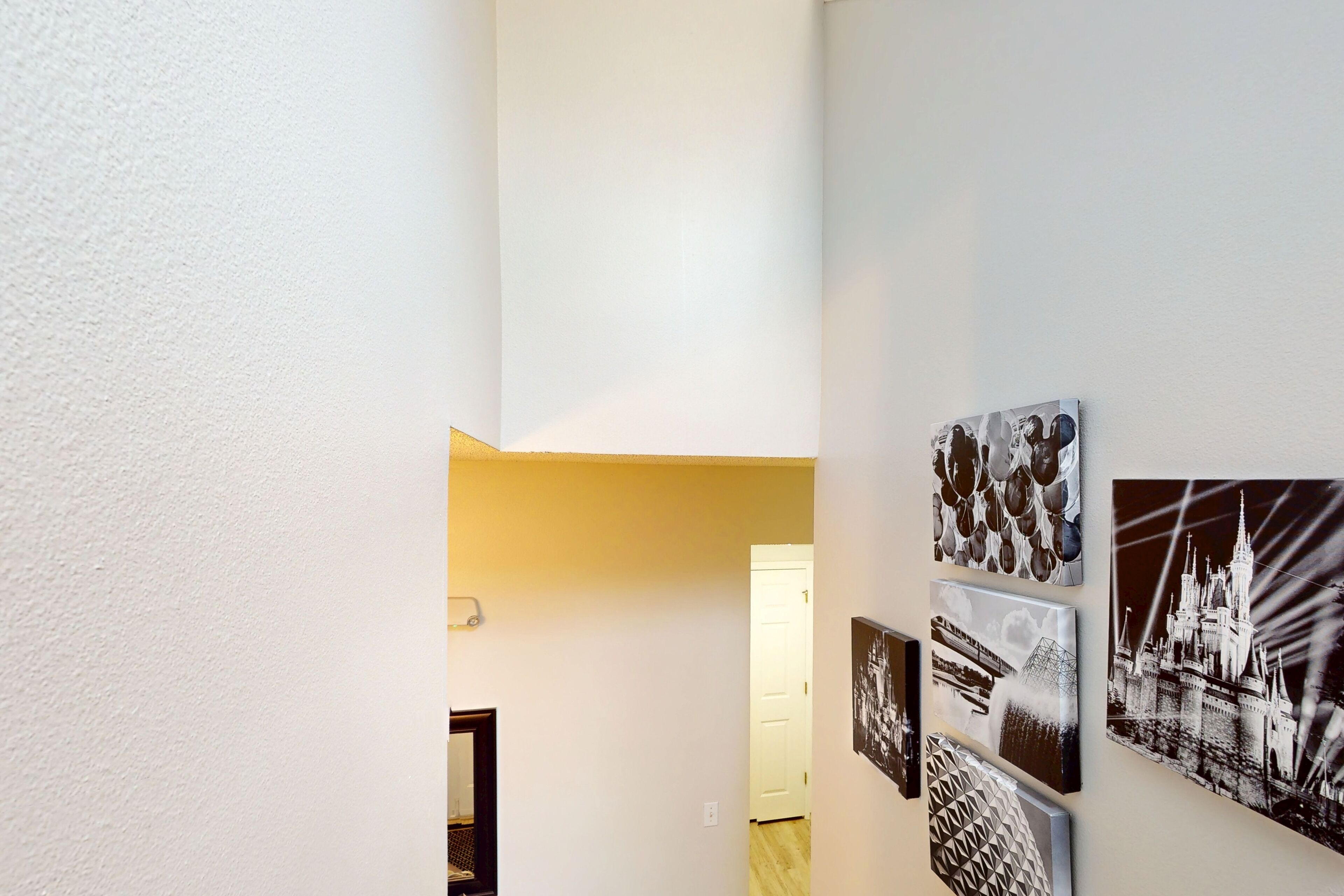 Un pasillo con una pared blanca y una puerta al final. Varias fotografías en blanco y negro decoran la pared.