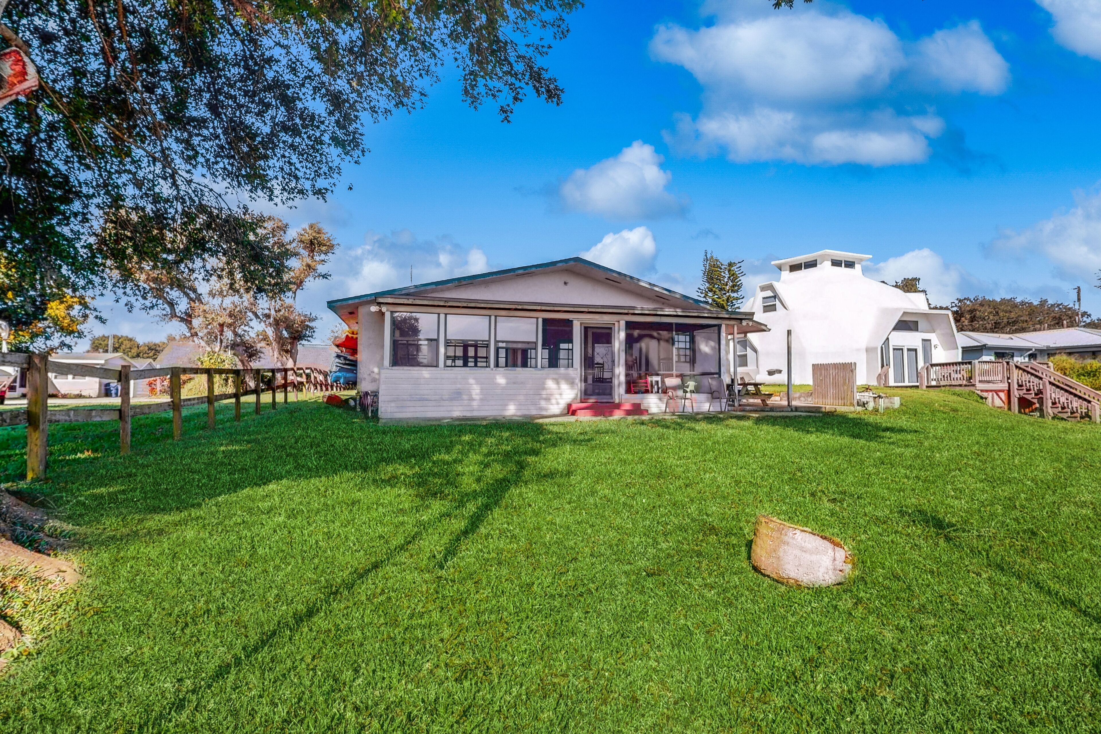 A modern house with a large lawn, a covered porch, and a wooden deck.