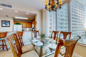 A dining area with a glass table, wooden chairs, and a chandelier. - Lakefront resort near attractions with AC, kitchen, hot tub, pool & lake view (Orlando)