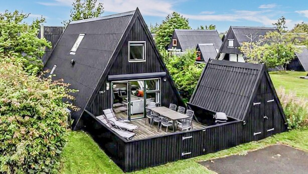 Uma casa preta com telhado triangular, com área de jantar e pequena cozinha.
