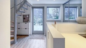 Um interior moderno com escada, área de escritório e grandes janelas com vista para uma paisagem nevada.
