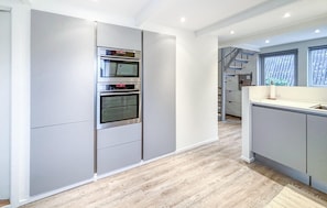 Eine moderne Küche mit eingebauten Backöfen und Holzboden.