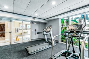 A gym with treadmills, a stationary bike, and a weight bench. - Welcoming lakefront condo with gorgeous lake view, kitchen, AC, pool & hot tub (Orlando)