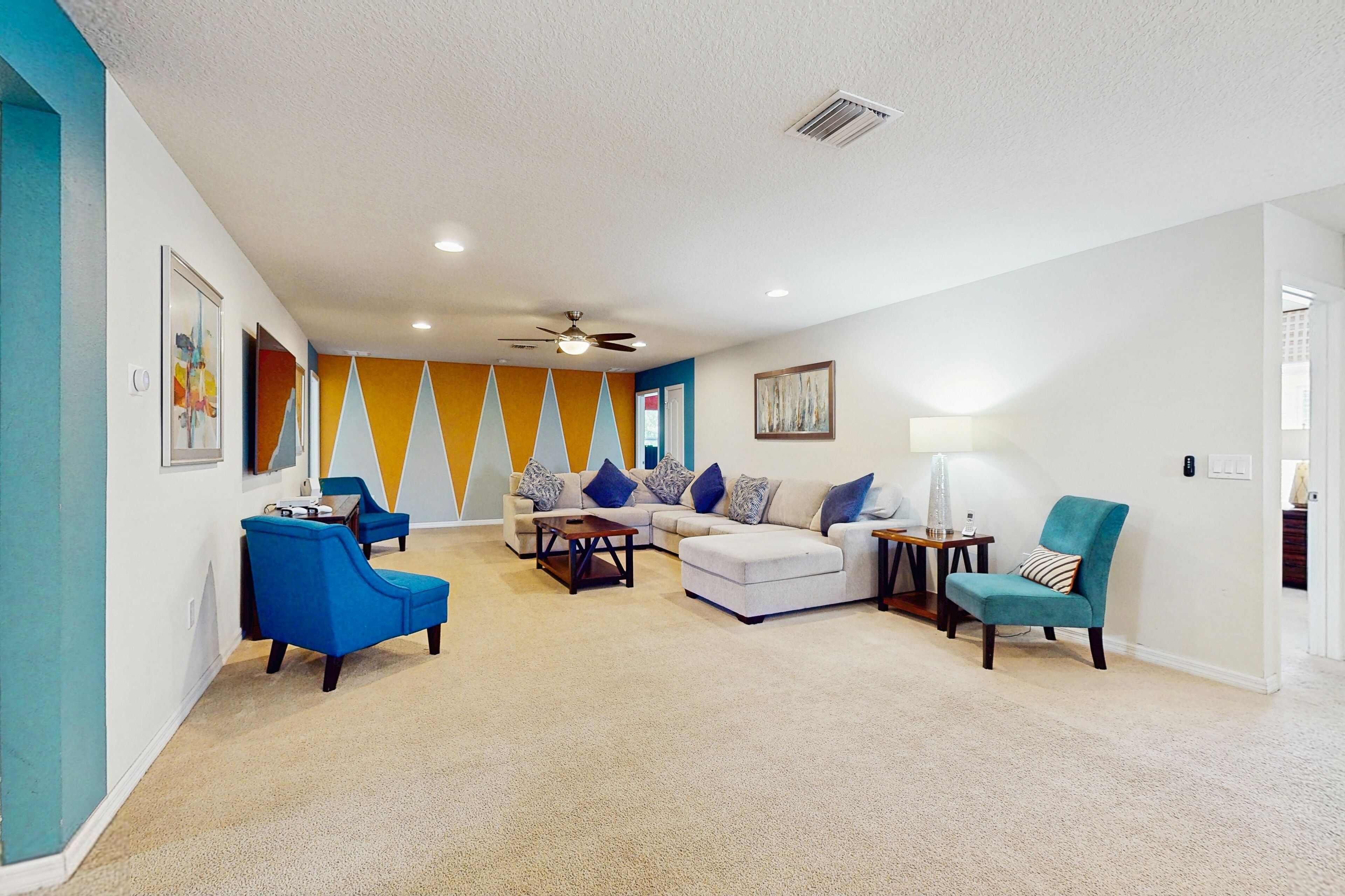 A living room with a sectional sofa, a blue armchair, and a teal armchair.