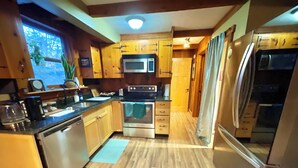 A compact kitchen with wooden cabinets, a microwave, an oven, and a refrigerator. - Log Cabin Mountain Retreat,  2-bedroom cabin in Mills River North Carolina (Horse Shoe)