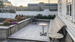 Une terrasse sur le toit avec un plancher en bois, deux tables rondes et deux chaises.