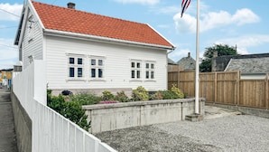A white house with a red-tiled roof, a flagpole with a flag, and a gravel driveway. - 2 bedroom stunning home in Haugesund (Haugesund)