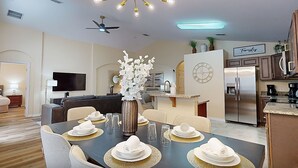 Ein modernes Wohnzimmer mit Essbereich, einer Küche und einem an der Wand befestigten Fernseher.