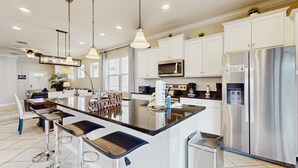 Una cocina moderna con una isla central, electrodomésticos de acero inoxidable e iluminación colgante.