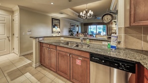 A kitchen with granite countertops, stainless steel appliances, wooden cabinets, and a chandelier. - Family-Friendly Condo with Access to Shared Pools, Hot Tub, and Game Rooms (Kissimmee)