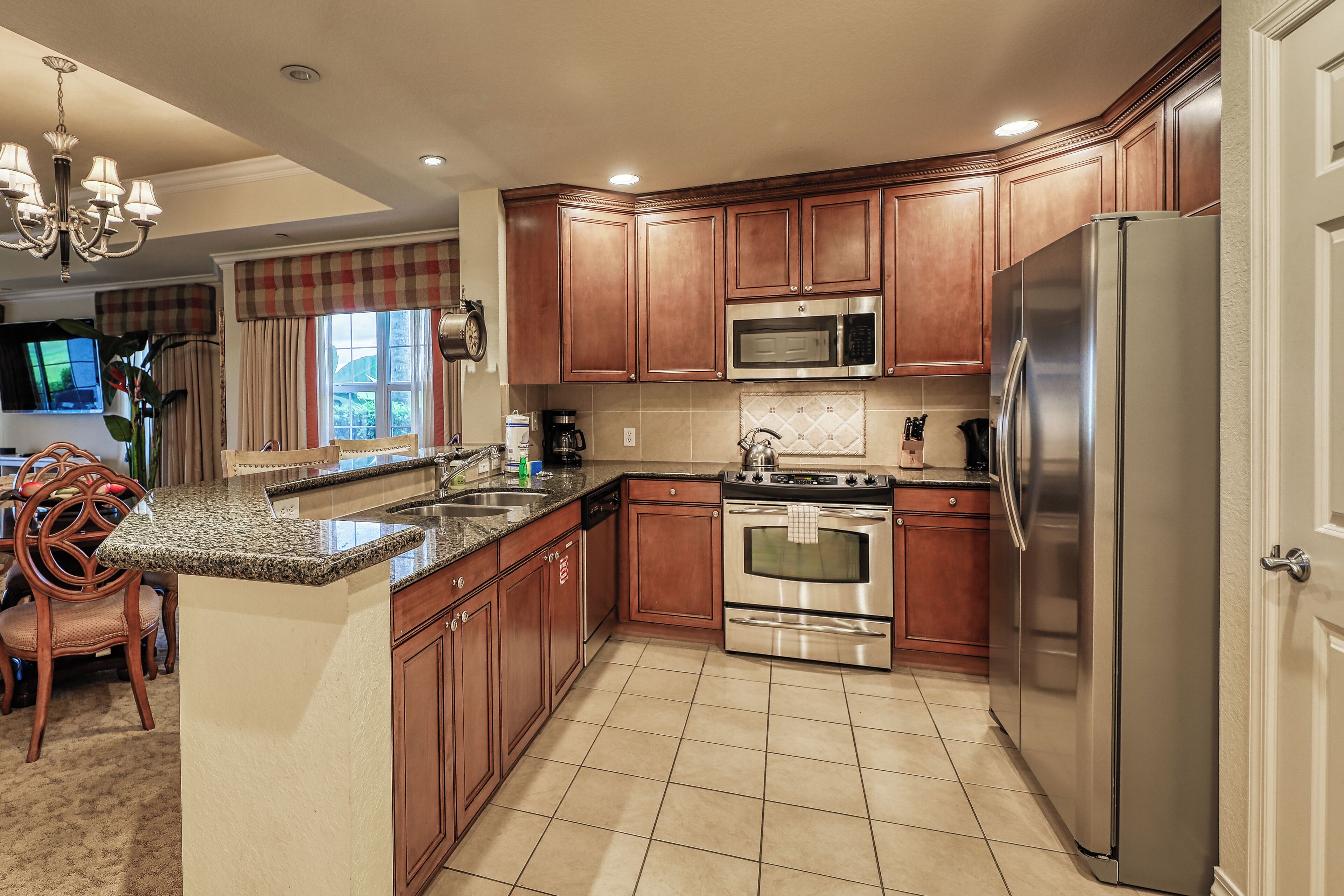 A kitchen with wooden cabinets, a stainless steel refrigerator, a microwave, and an oven.