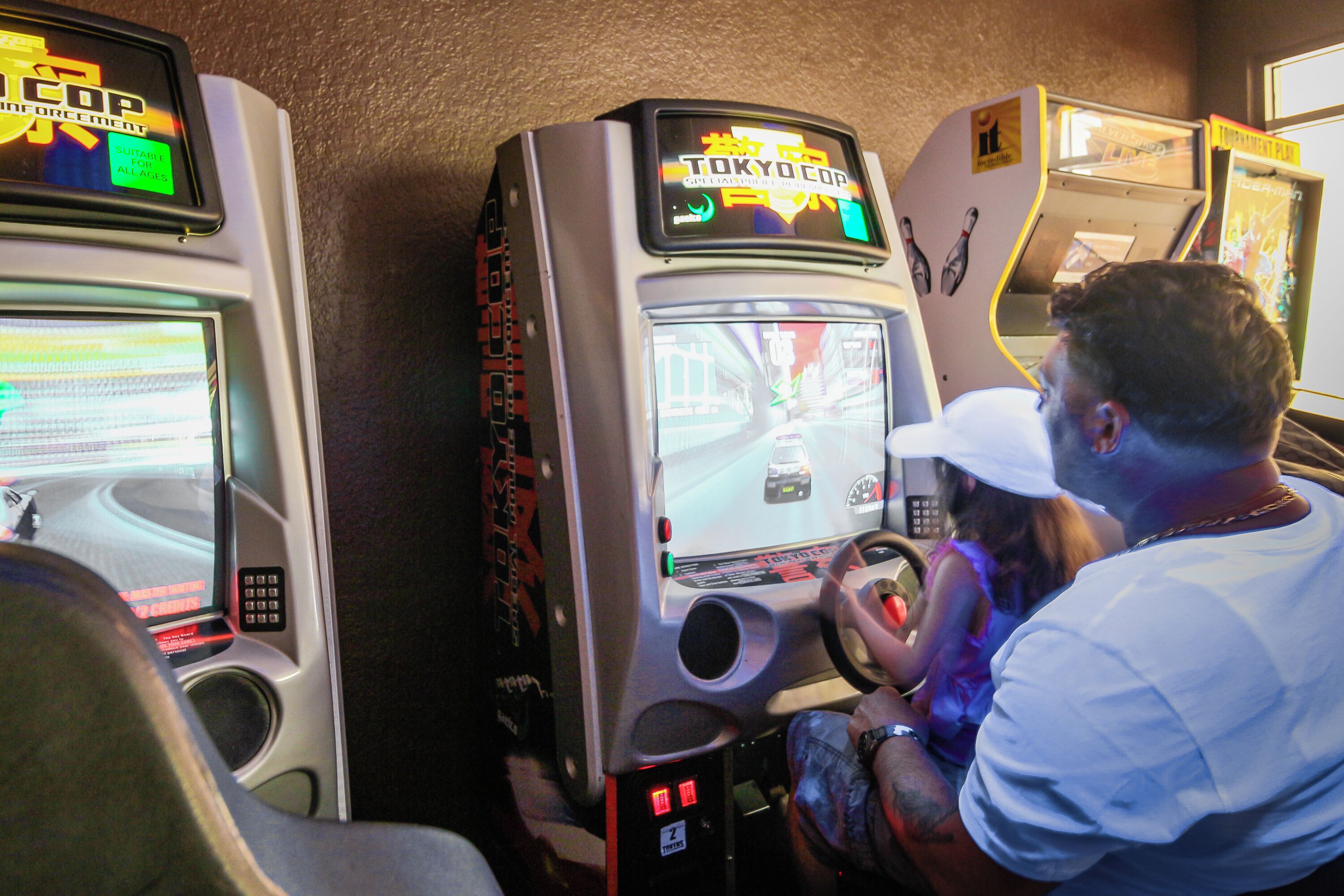 A video game arcade with racing games, including a 'Tokyo Cop' game.