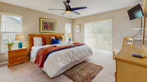 A bedroom with a bed, a ceiling fan, a desk, and a TV. - Inviting pool home with tranquil pond view near theme parks & attractions (Kissimmee)