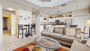 Una sala de estar moderna con una mesa de centro de vidrio, un sofá color beige y un comedor con mesa y sillas.