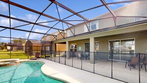Piscina cubierta al aire libre con cerramiento de vidrio, zona de patio contigua con mobiliario exterior y vistas del vecindario.