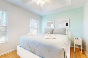 Un dormitorio con una cama grande, dos mesitas de noche y un ventilador de techo.