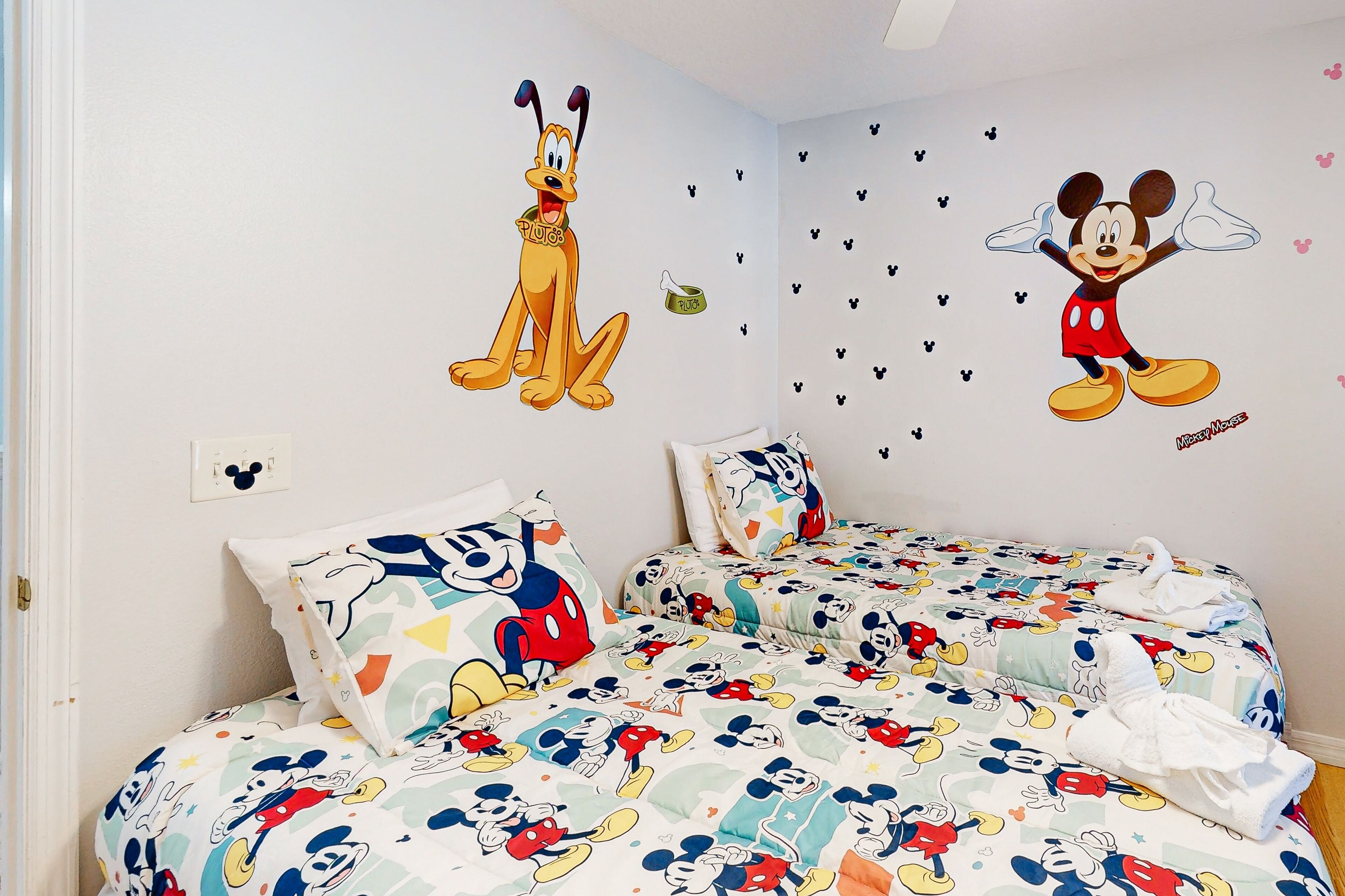 Ett hotellrum med väggdekorationer med Kalle Anka och Pluto, två sängar med Kalle Anka-tema och en kudde med Kalle Anka-motiv.