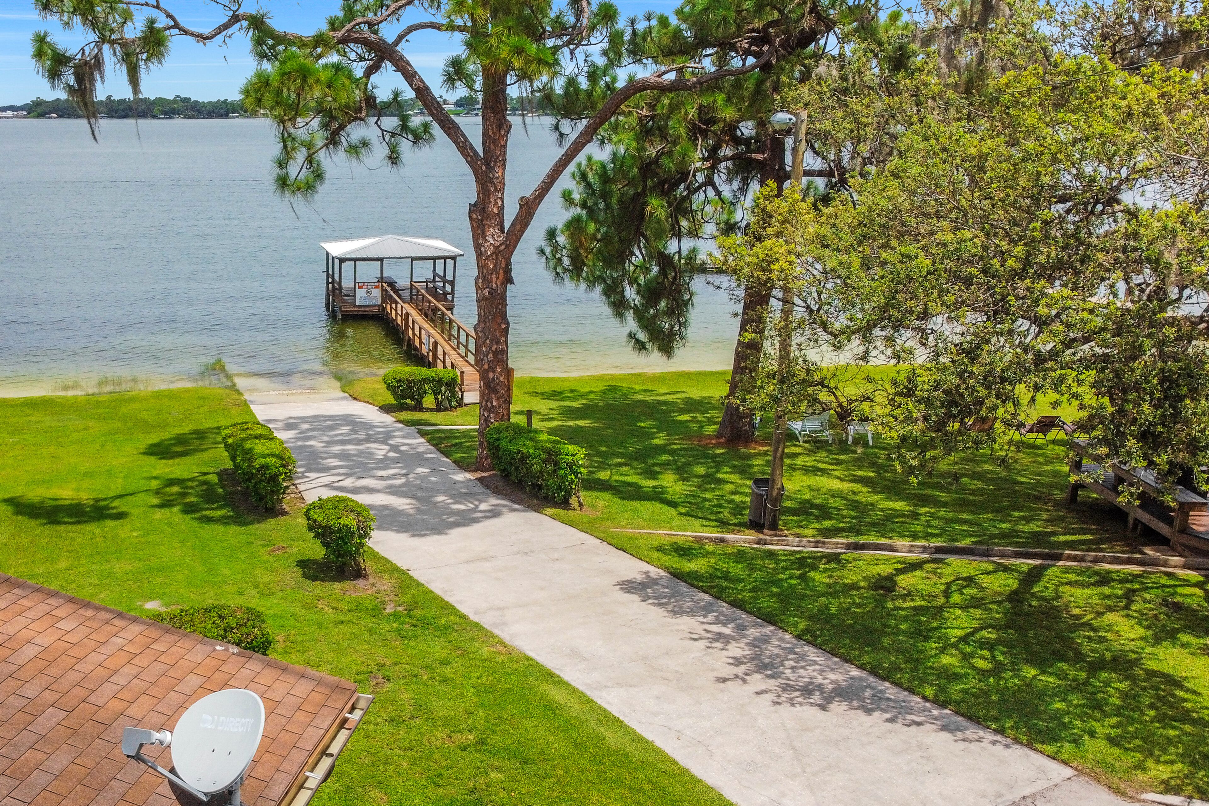 Um imóvel à beira do lago com um coreto, um caminho pavimentado e jardins bem cuidados.