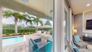 Un espacio exterior moderno con piscina, mobiliario de mimbre y vistas al jardín.
