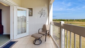 A balcony with two wicker chairs, a white door with glass panels, and a decorative wall piece.
