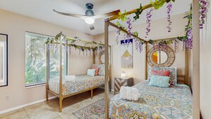Ein Schlafzimmer mit zwei Betten, einem Deckenventilator und dekorativen Hängepflanzen.