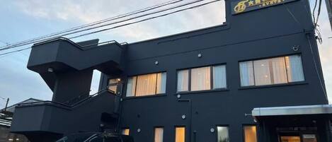 A modern building with a black exterior and a sign for the Garden Hotel.