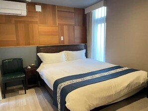 A neatly made bed with a wooden headboard, a bedside table with a lamp, and a chair. - daido garden hotel kyoto (Kyoto)