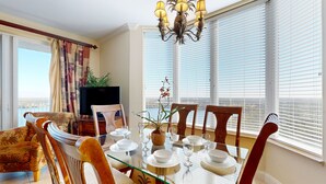 A dining area with a glass table set for four, surrounded by wooden chairs. - Lakefront condo near Disney with lake and city view, pool, hot tub, AC & WiFi (Orlando)