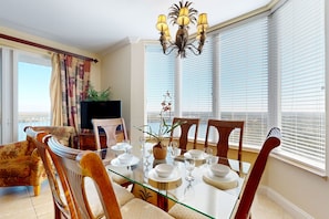 Een eetruimte met een glazen tafel, houten stoelen en een kroonluchter.