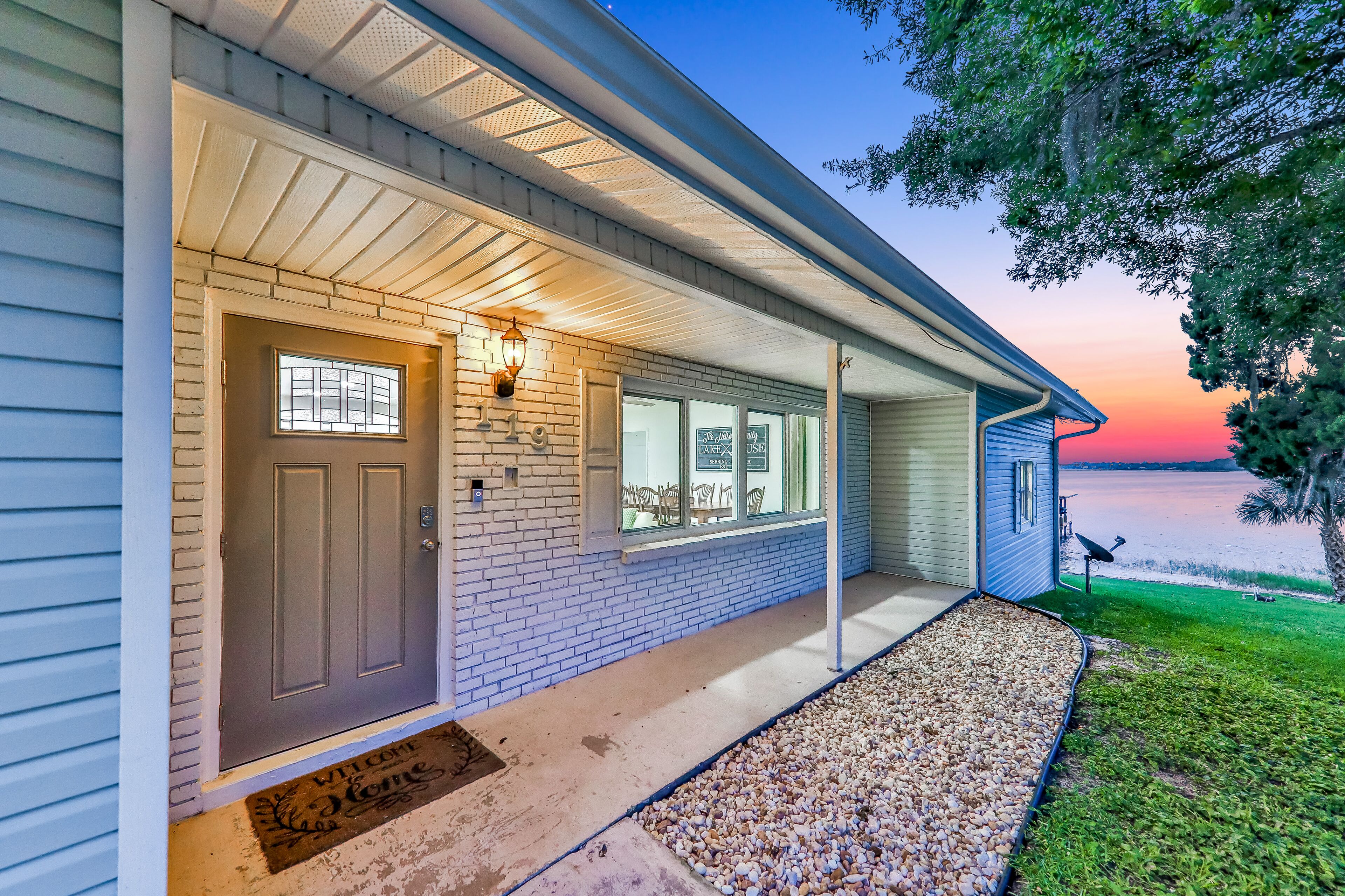 A house with a front porch, a brick wall, and a view of the water.