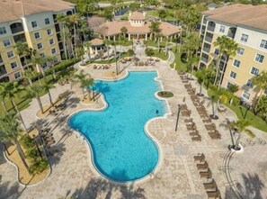 Ein Resort mit großem Schwimmbecken, mehreren Gebäuden und Palmen.
