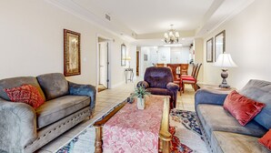 A spacious living room with a large sofa, a coffee table, and a dining area in the background. - Lakefront condo with pool, hot tub, balcony & prime location for theme parks (Orlando)
