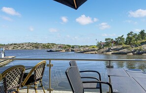 A deck with chairs overlooking a body of water, a dock with boats, and a rocky shoreline with buildings. - Nice home in Vesterøy with WiFi (Vesterøy)