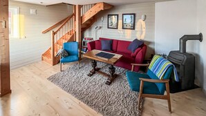 Ein gemütliches Wohnzimmer mit einer Holztreppe, einem roten Sofa, einem blauen Sessel, einem Couchtisch und einem Kamin.