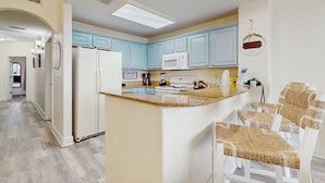 Una cocina moderna con armarios azul claro, un refrigerador blanco y una isla central con sillas.