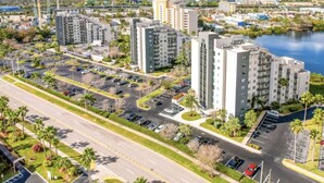 A high-rise building complex with multiple parking lots and a river in the background. - Spacious Condo with a Kitchen, AC, Pools, Hot Tubs, Tennis, & Gym (Orlando)