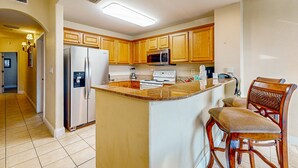 Una cocina con armarios de madera, un refrigerador de acero inoxidable, un microondas y una estufa.