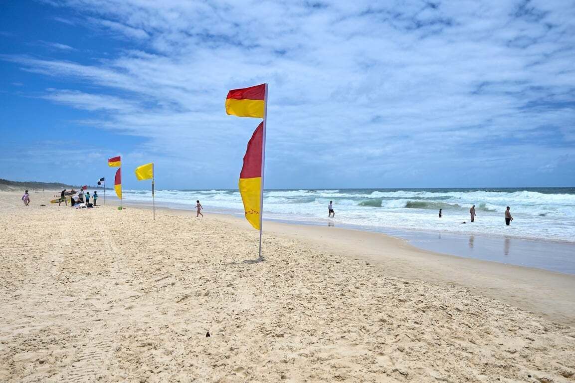 Una playa con banderas y gente.