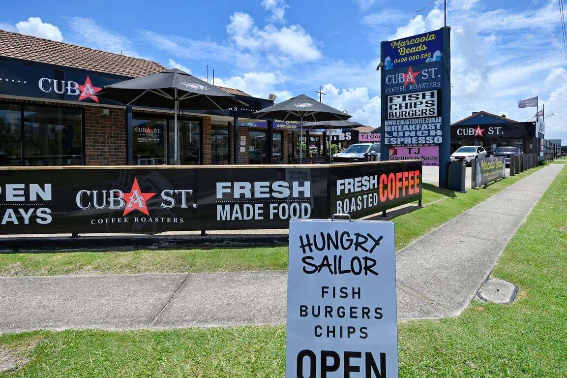 Une devanture de magasin avec des panneaux indiquant « CUBA ST. COFFEE ROASTERS » et « NOURRITURE FRAÎCHE ».