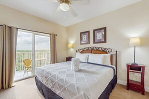 A hotel room with a large bed, a balcony with a chair, two bedside lamps, and two framed pictures on the wall. - Classy lakefront condo, w/ shared pool, hot tub, & fitness center - near Disney (Orlando)